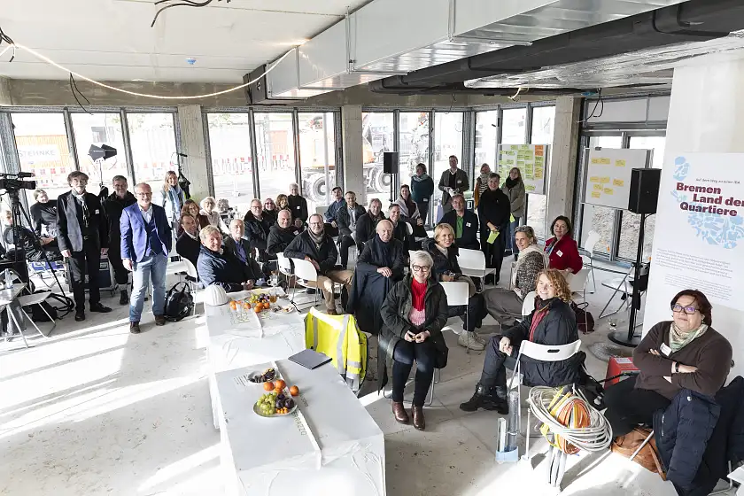 Gruppenfoto vom Think Tank-Treffen. Leute stehen in einem Raum uns schauen zur Kamera herauf.